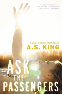 Cover of "Ask the Passengers," with the title in big white font at the bottom, over a photo of a white femme person raising their hand into a bright sky against a natural backdrop. There's a lens flare in the center of the image.