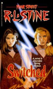 cover of "Switched," featuring the title in lurid red font at the bottom, over an image of 2 white girls (one brown-haired, one blonde) in identical read dresses staring out, with a white lightning bolt separating them