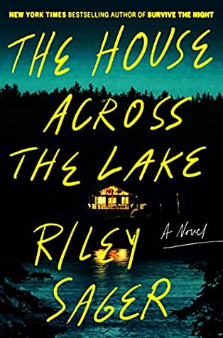 Cover of "The House Across the Lake," featuring the title in bright, thin yellow letters against a photo of a lakehouse lit up from within, at dusk