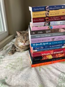 Tib sticking her tongue out next to my TBR pile